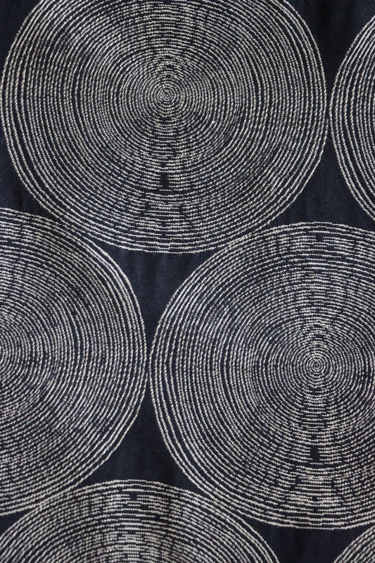 Detailed close-up of the Adam Black fabric from Arte Fresca Outlet, highlighting the intricate woven texture and the subtle color variations within the cream and beige concentric circles against the rich, almost night-black background.