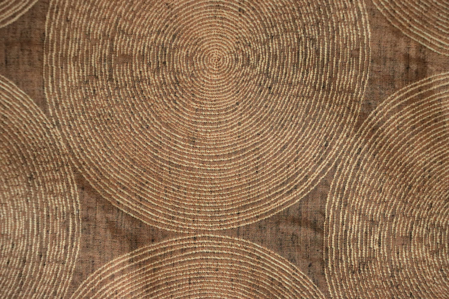 Close-up of Voisin Gold fabric by Arte Fresca Outlet, highlighting its fine weave, subtle cream concentric circles, and warm copper tones, revealing the tactile appeal and quality.