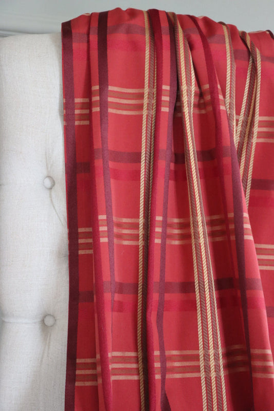 BRAXTON CHECK RASPBERRY fabric from ARTE FRESCA Outlet draped casually over a light-colored chair back, illustrating the scale of its classic check pattern. Perfect for assessing how this British-inspired textile will look in your home.