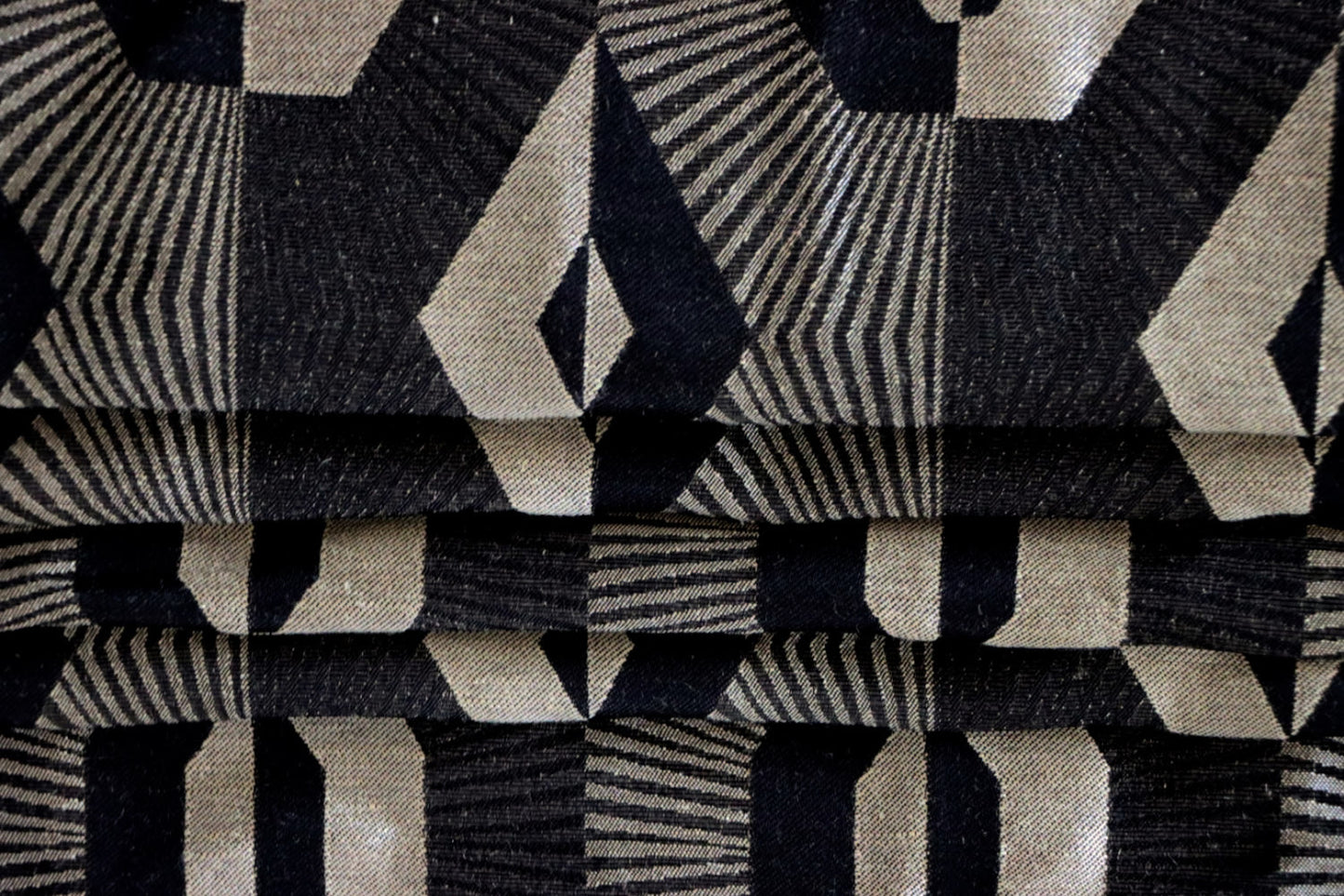 Voisin Black fabric by Arte Fresca Outlet arranged in folds, envisioning its application as a stylish Roman blind that adds a graphic touch to any window.