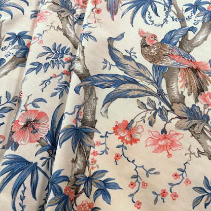 Close-up of ALLEGRIA BLUE/CREAM fabric coupon from Arte Fresca Outlet, showcasing the intricate details of the tropical pattern. A colorful parrot, hibiscus flowers, and leaves are depicted with fine lines and careful drawing in blue, red, and beige on a cream 100% cotton textile, highlighting its exquisite quality.