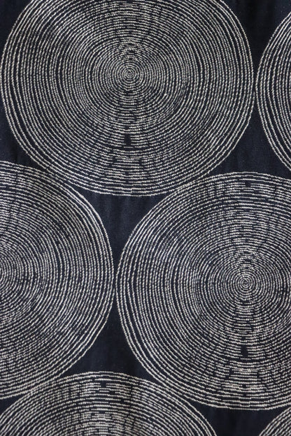   Detailed close-up of the Adam Black fabric from Arte Fresca Outlet, highlighting the intricate woven texture and the subtle color variations within the cream and beige concentric circles against the rich, almost night-black background.