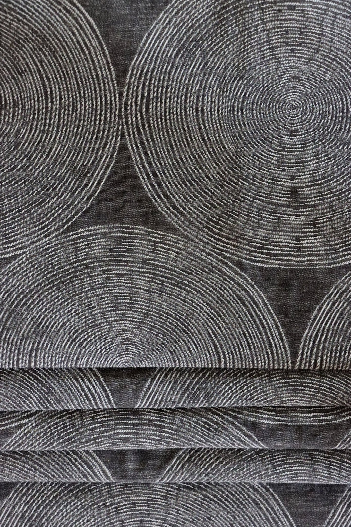 ADAM CHARCOAL fabric by Arte Fresca Outlet, folded precisely like a Roman blind, highlighting its structured yet adaptable nature, the elegant concentric circle pattern, and its ability to create clean, sophisticated window coverings.