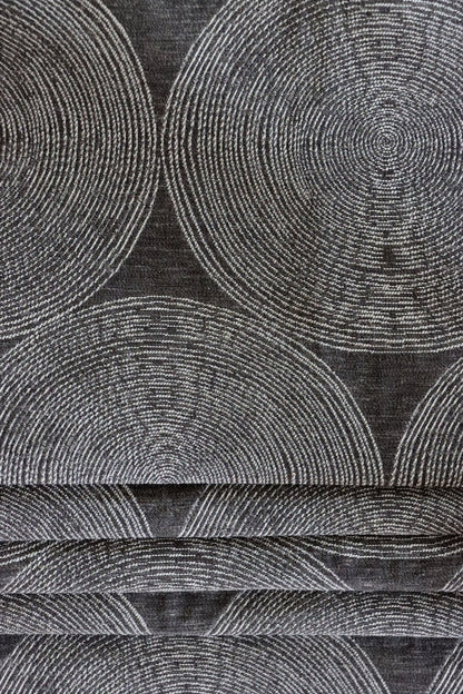 ADAM CHARCOAL fabric by Arte Fresca Outlet, folded precisely like a Roman blind, highlighting its structured yet adaptable nature, the elegant concentric circle pattern, and its ability to create clean, sophisticated window coverings.