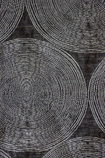 Close-up of ADAM CHARCOAL fabric from Arte Fresca Outlet, revealing the fine weave, the subtle texture within its concentric cream and silver-grey circles on deep anthracite, emphasizing its quality and sophisticated detail.