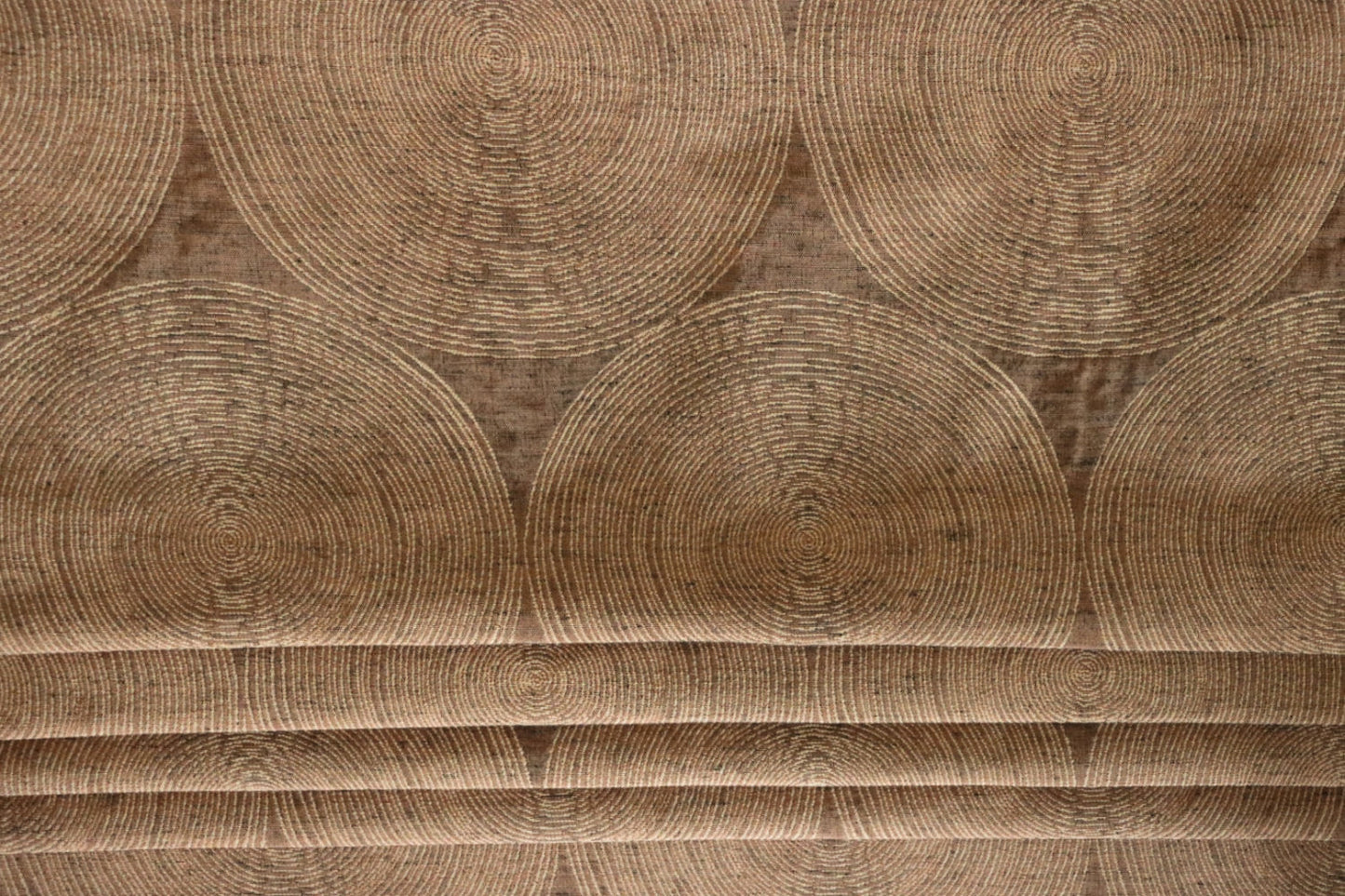 Voisin Gold fabric by Arte Fresca Outlet folded like a Roman blind, illustrating its structured appearance and warm copper and cream concentric circle pattern, perfect for window treatments.
