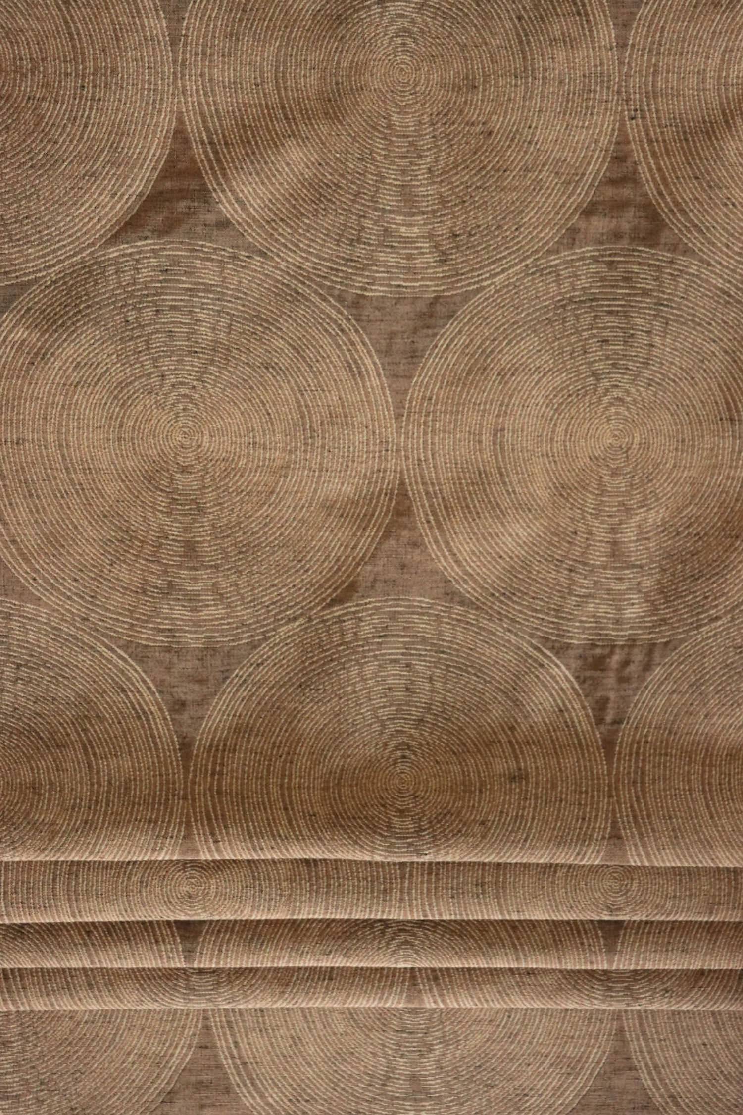 Voisin Gold fabric by Arte Fresca Outlet folded like a Roman blind, illustrating its structured appearance and warm copper and cream concentric circle pattern, perfect for window treatments.
