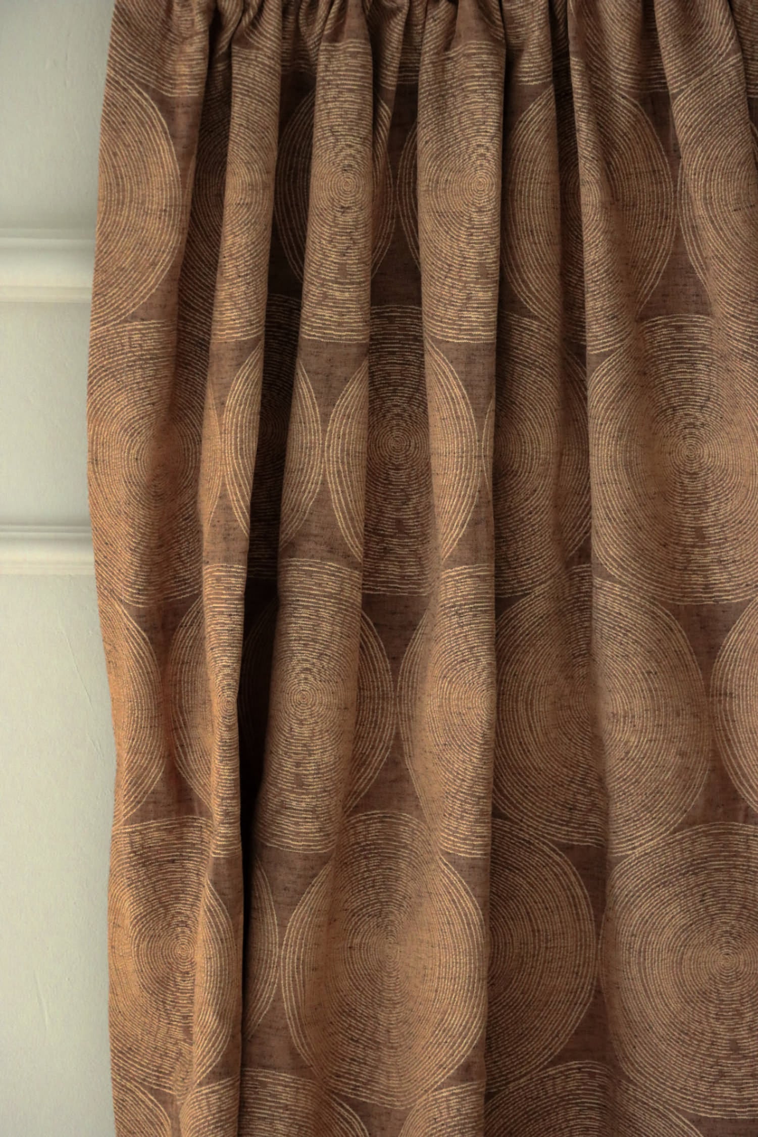 Voisin Gold fabric by Arte Fresca Outlet elegantly folded, demonstrating its beautiful drape and suitability as a curtain fabric, revealing the subtle concentric circle pattern and rich copper color.