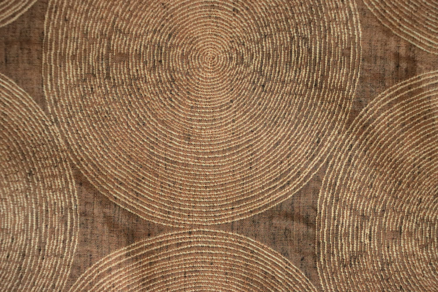 Close-up of Voisin Gold fabric by Arte Fresca Outlet, highlighting its fine weave, subtle cream concentric circles, and warm copper tones, revealing the tactile appeal and quality.