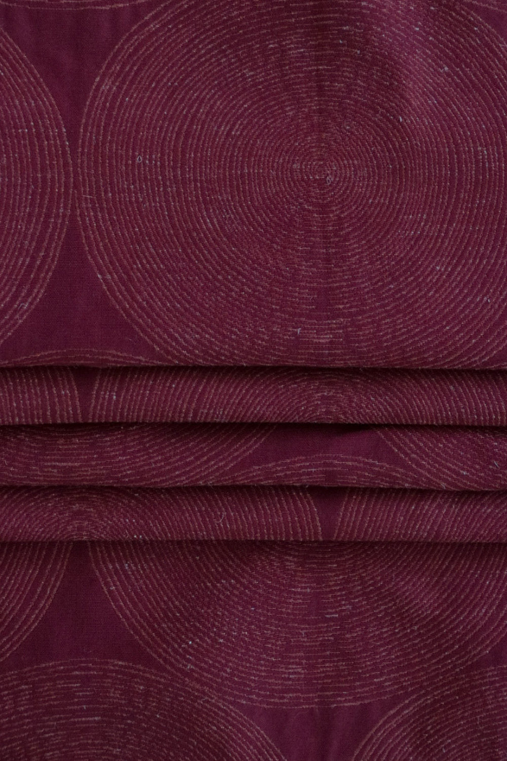 ADAM RED fabric by Arte Fresca Outlet, folded precisely like a Roman blind, highlighting its structured yet adaptable nature, the deep red geometric pattern with relief, and its ability to create sophisticated, well-defined window coverings.