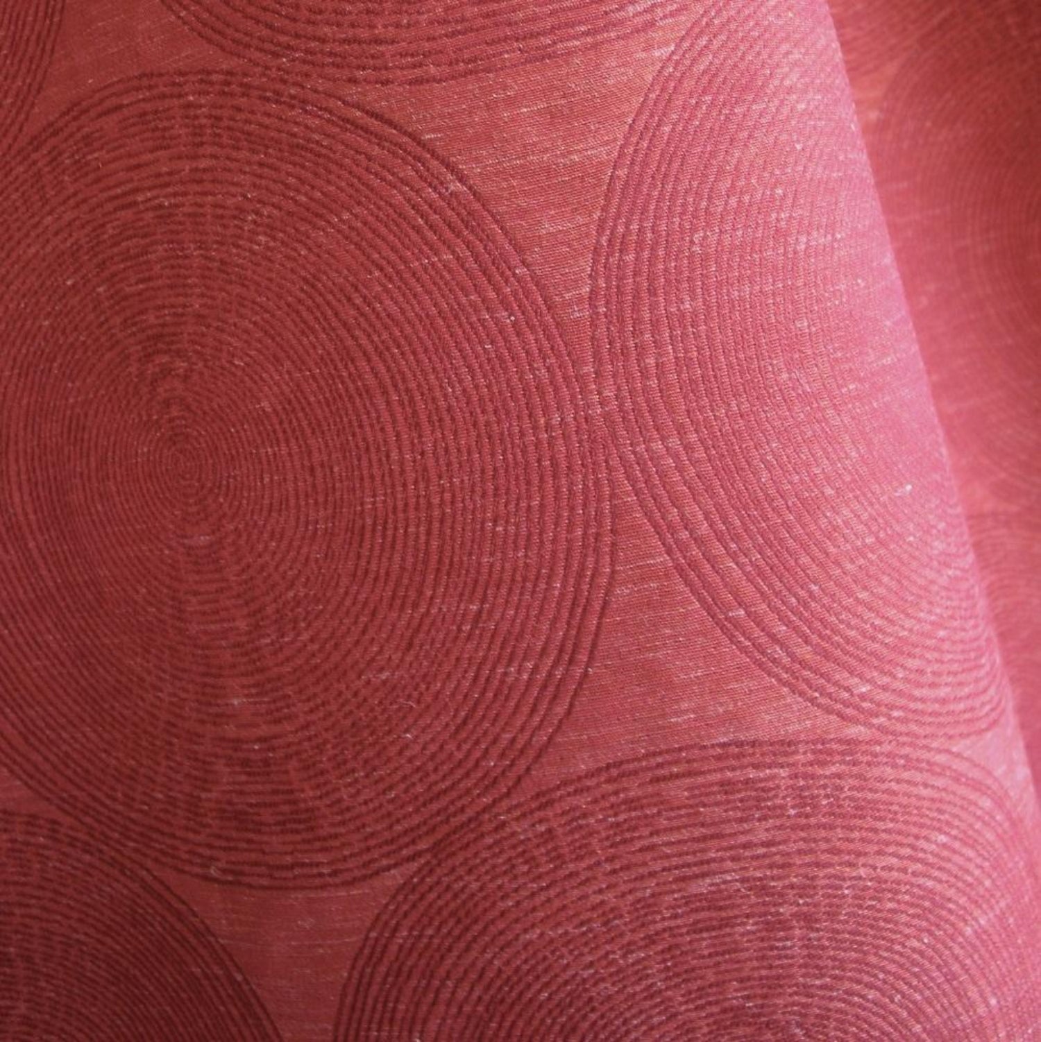 Close-up of ADAM RED fabric from Arte Fresca Outlet, revealing the intricate woven details of its overlapping concentric circle pattern, the relief texture, and the rich, shimmering burgundy to brick red tones with slight variations.