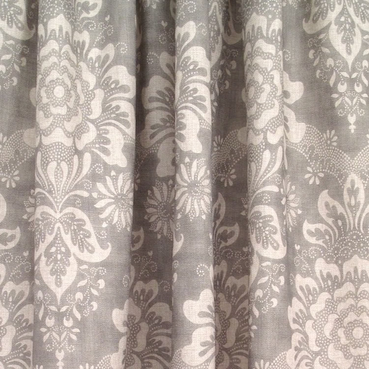 Adele Grey fabric by Arte Fresca Outlet elegantly folded, demonstrating its beautiful drape and suitability as a curtain fabric, revealing the classic floral pattern in soft grey and ivory.