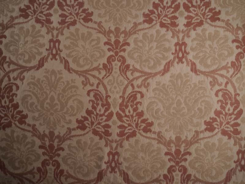 Damask patterned in warm beige and muted terracotta red.