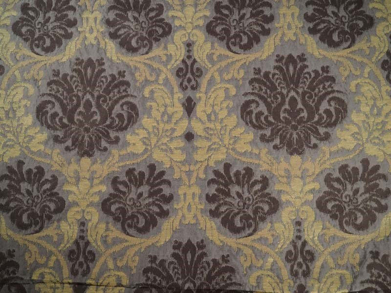 Damask patterned fabric with dark brown floral motifs and gold scrollwork on a muted gray background.