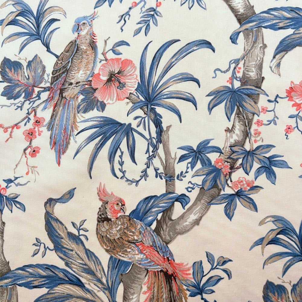 ALLEGRIA BLUE/CREAM fabric coupon by Arte Fresca Outlet, a reduced French 100% cotton remnant. It features a detailed tropical design with a vibrant parrot amidst lush hibiscus blossoms and gentle foliage in soft blue, red, and warm beige tones on a cream background, perfect for small sewing projects.
