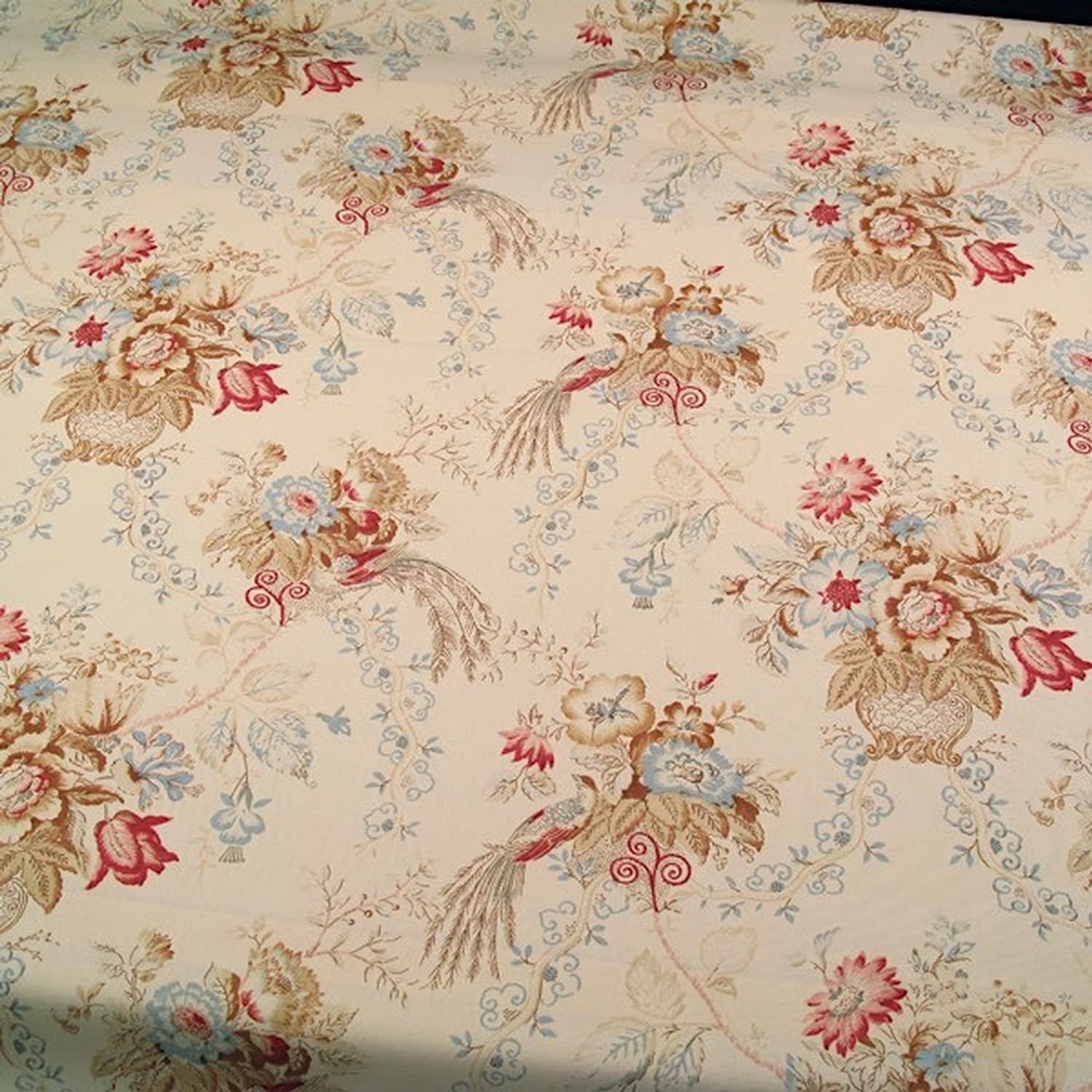 A length of ALLISON CREAM fabric casually draped over a light-colored chair back. The image demonstrates the flexible drape and the scale of the floral pattern in a decorative setting.