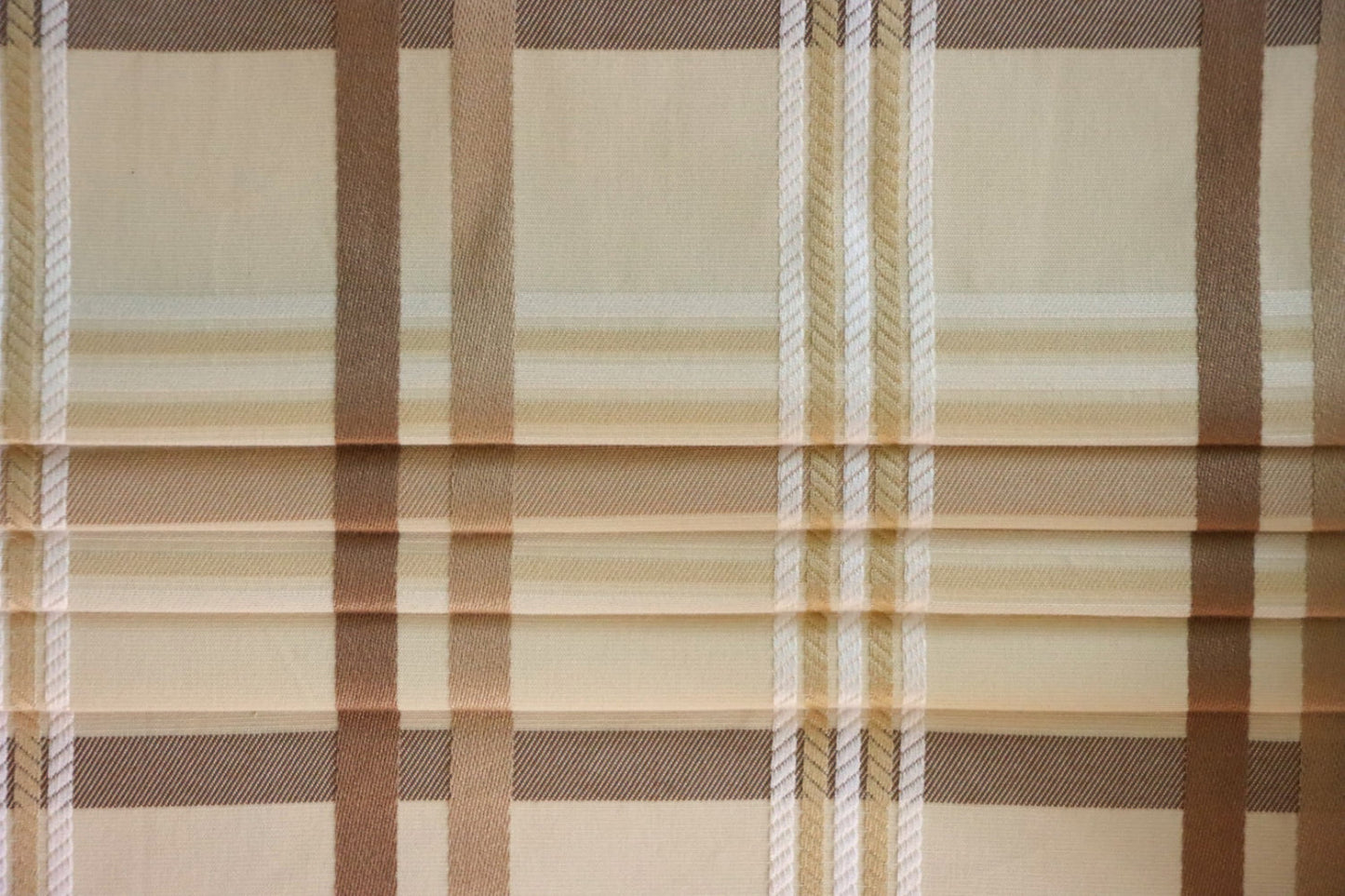 Braxton Check fabric artfully folded like a window blind, displaying its crisp lines and the timeless beige and brown plaid design, perfect for custom blinds from Arte Fresca Outlet.