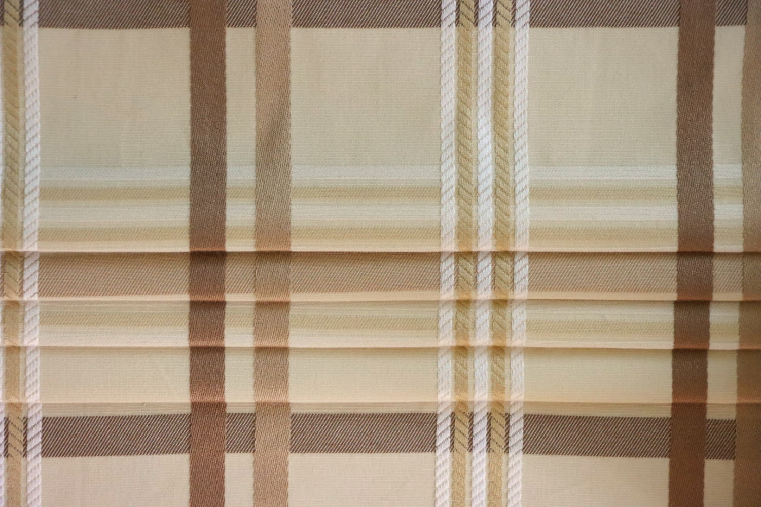 Braxton Check fabric artfully folded like a window blind, displaying its crisp lines and the timeless beige and brown plaid design, perfect for custom blinds from Arte Fresca Outlet.