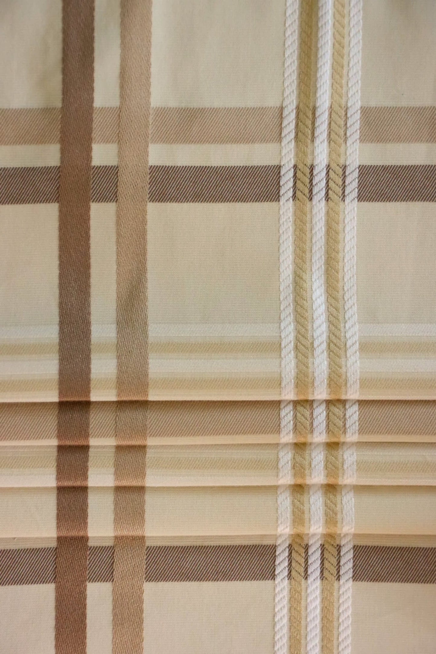 Braxton Check fabric artfully folded like a window blind, displaying its crisp lines and the timeless beige and brown plaid design, perfect for custom blinds from Arte Fresca Outlet.