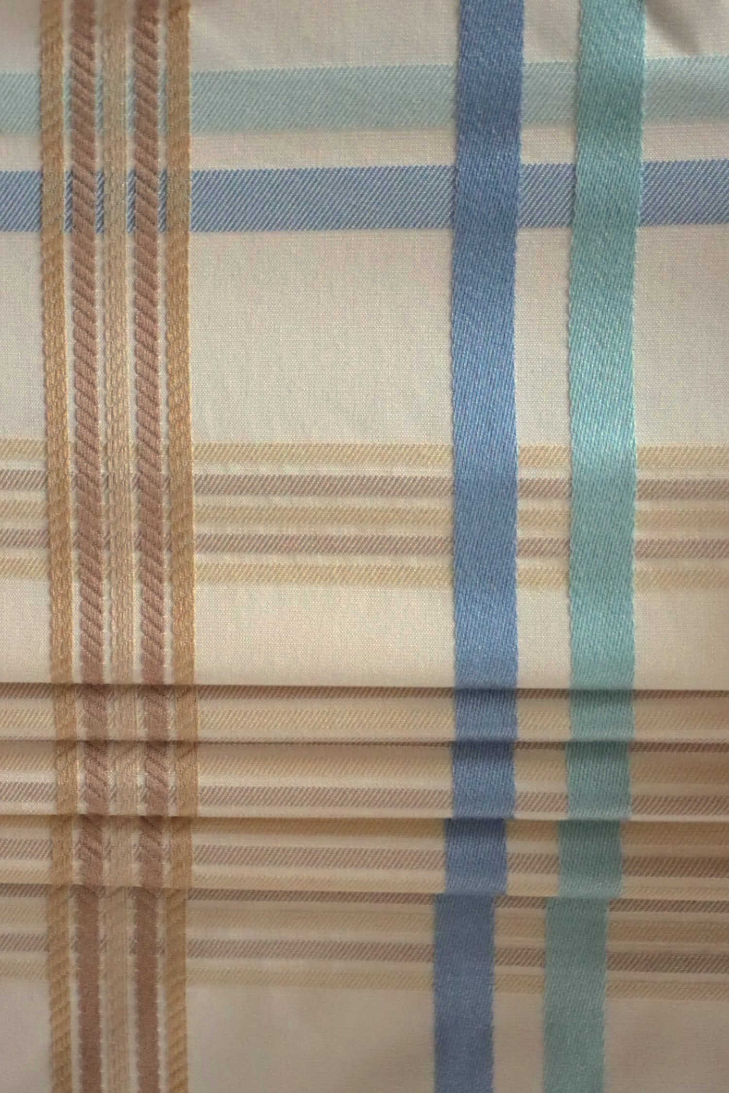 BRAXTON CHECK BLUE/CREAM fabric by Arte Fresca Outlet, folded precisely like a Roman blind, highlighting its structured yet soft nature, the clean lines of the blue, cream, and brown check, and its suitability for elegant blind designs.