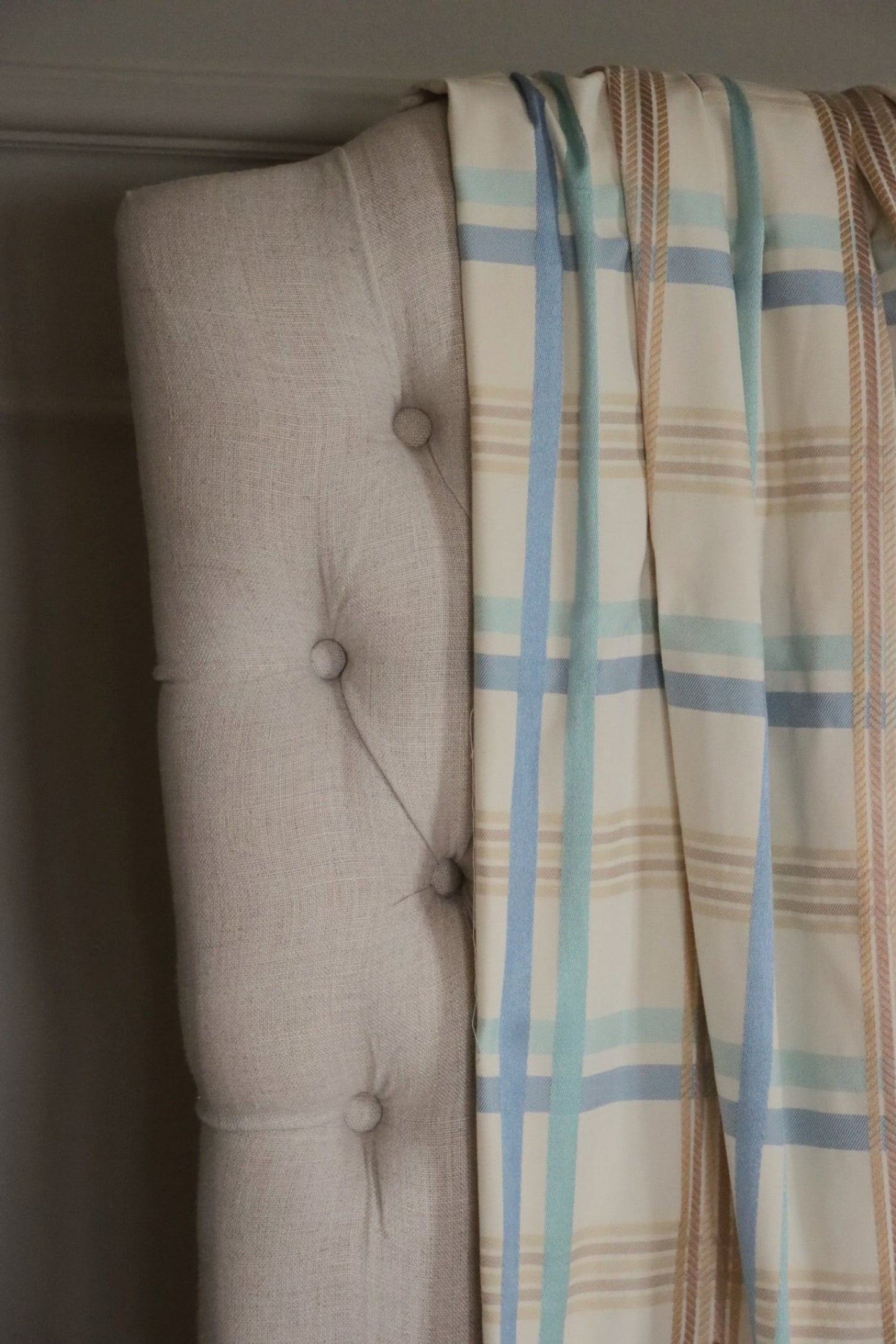 BRAXTON CHECK BLUE/CREAM fabric by Arte Fresca Outlet draped loosely over a light upholstered chair back, illustrating the scale of its classic check pattern in blue, cream, and brown, ideal for assessing design repeat.