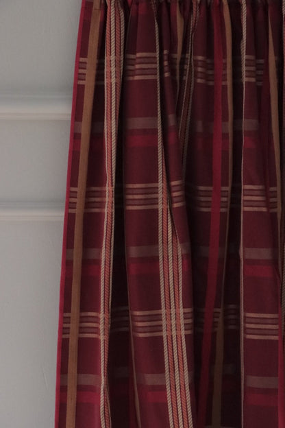 Braxton Check Burgundy fabric by Arte Fresca Outlet elegantly folded, demonstrating its beautiful drape and suitability as a curtain fabric, revealing the sophisticated plaid in burgundy, gold, and beige.