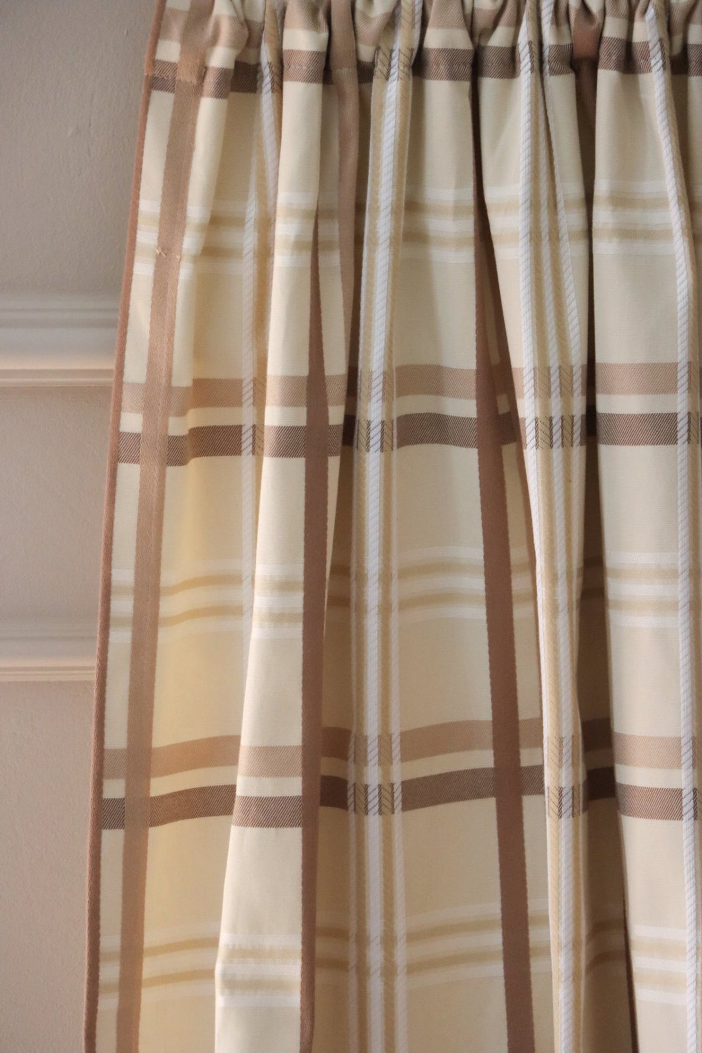 Braxton Check fabric elegantly folded like a curtain, showcasing its beautiful drape and the classic beige and brown plaid pattern for home decor, from Arte Fresca Outlet.