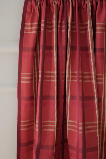 BRAXTON CHECK RASPBERRY fabric from ARTE FRESCA Outlet elegantly folded, resembling a curtain. This image demonstrates the fabric's beautiful drape and how its vibrant check pattern enhances light and adds warmth to a room.