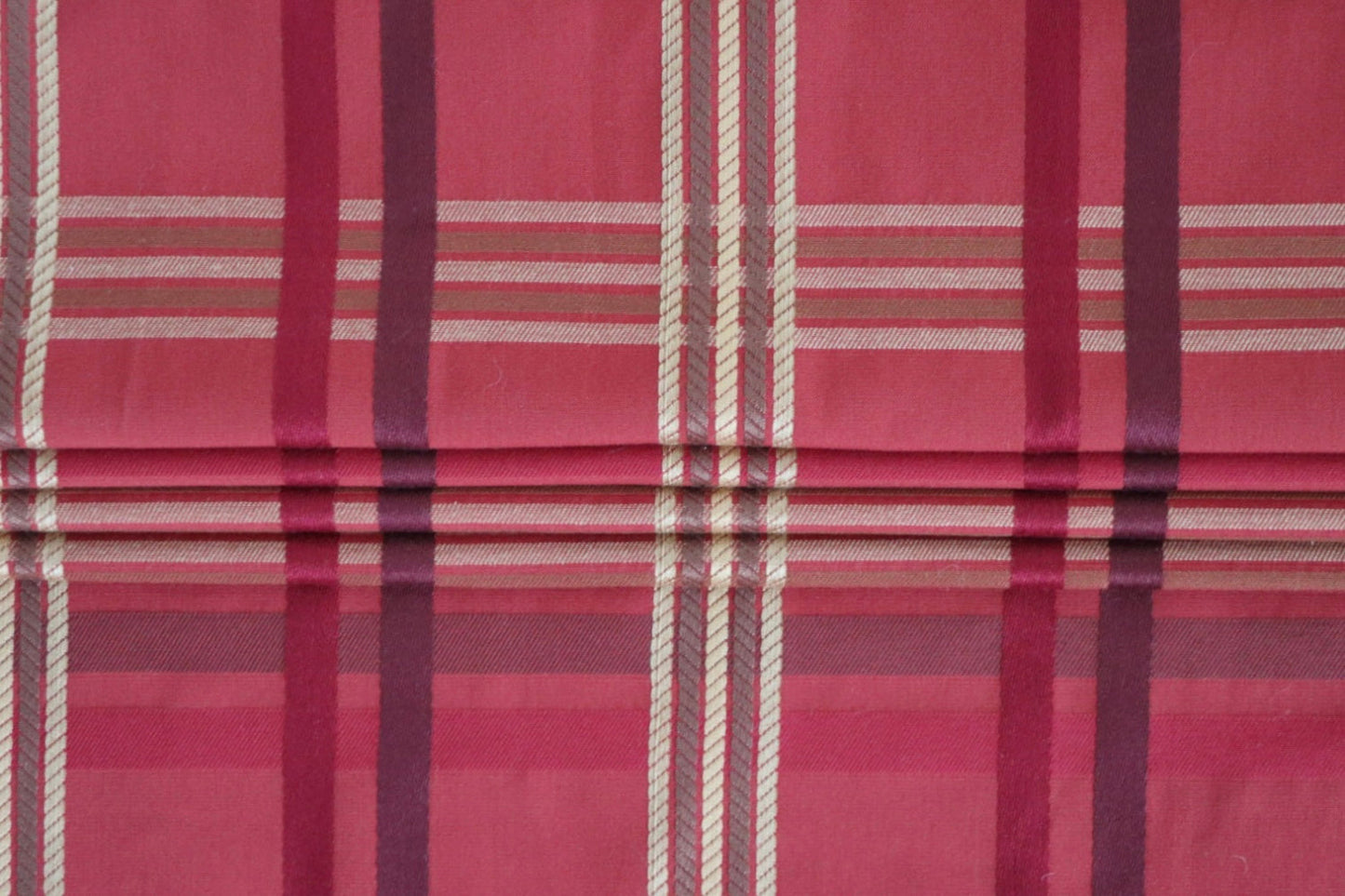 BRAXTON CHECK RASPBERRY fabric from ARTE FRESCA Outlet arranged to show its suitability for Roman blinds. The structured folds highlight the crispness of the check pattern, perfect for adding a touch of British elegance to windows.