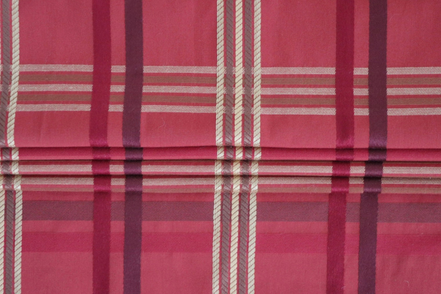 BRAXTON CHECK RASPBERRY fabric from ARTE FRESCA Outlet arranged to show its suitability for Roman blinds. The structured folds highlight the crispness of the check pattern, perfect for adding a touch of British elegance to windows.