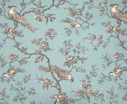 A large view of the Conway Ciel French cotton fabric from Arte Fresca Outlet, featuring a romantic, grey bird and branch pattern on a soft turquoise background.