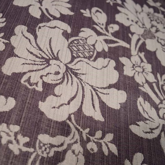 Close-up of MARY AUBERGINE jacquard fabric from Arte Fresca Outlet, revealing the intricate details of its large floral pattern, the rich aubergine and beige tones, and the tactile, raised texture characteristic of jacquard weaving.