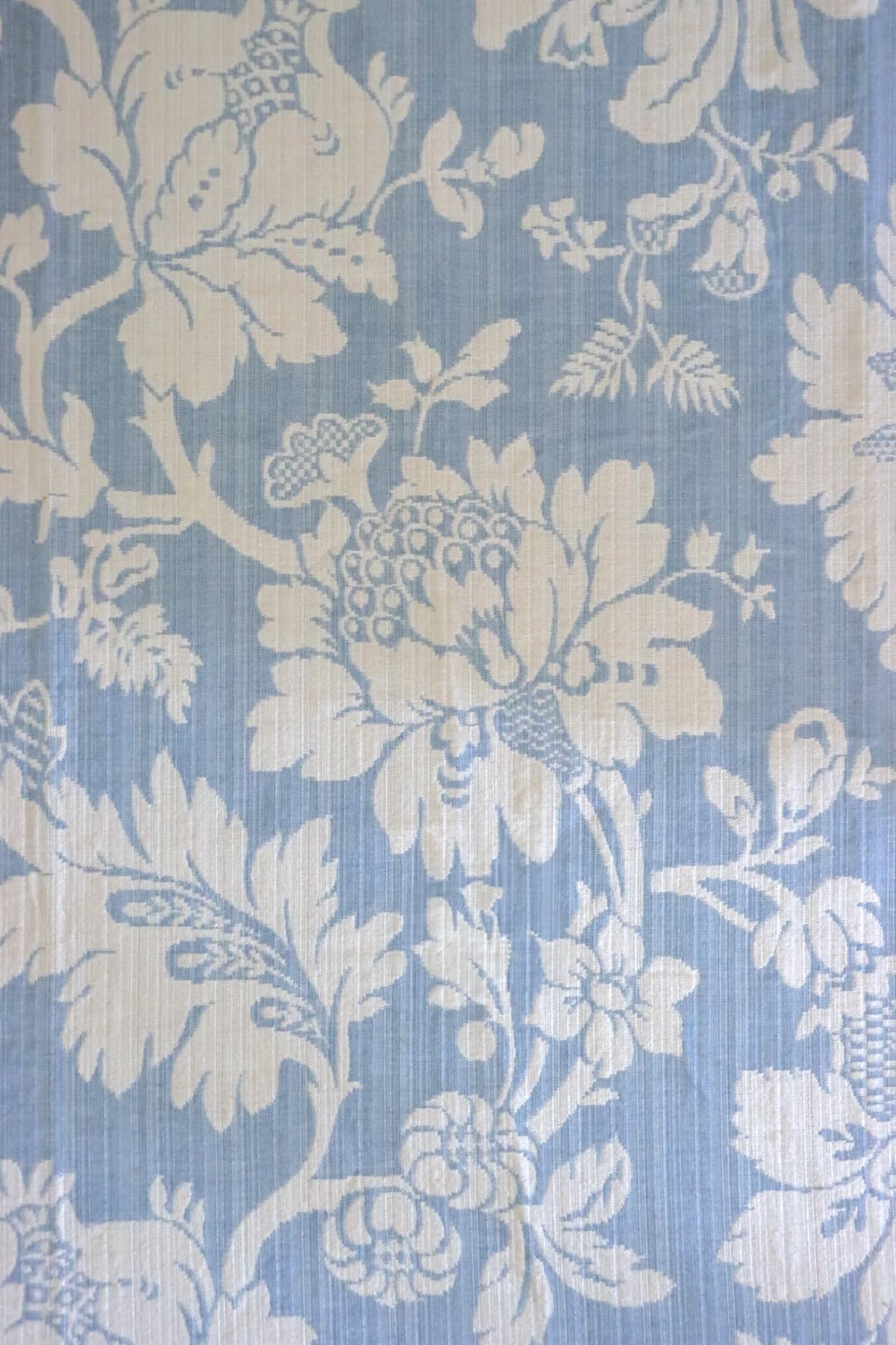 Close-up of Mary Light Blue jacquard fabric by Arte Fresca Outlet, highlighting the intricate white floral motif and luxurious texture on a soft powder blue background.