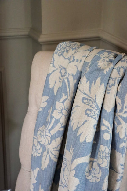 Mary Light Blue jacquard fabric from Arte Fresca Outlet loosely draped over a light upholstered chair back, showcasing the pattern size and elegant flow for home interiors.