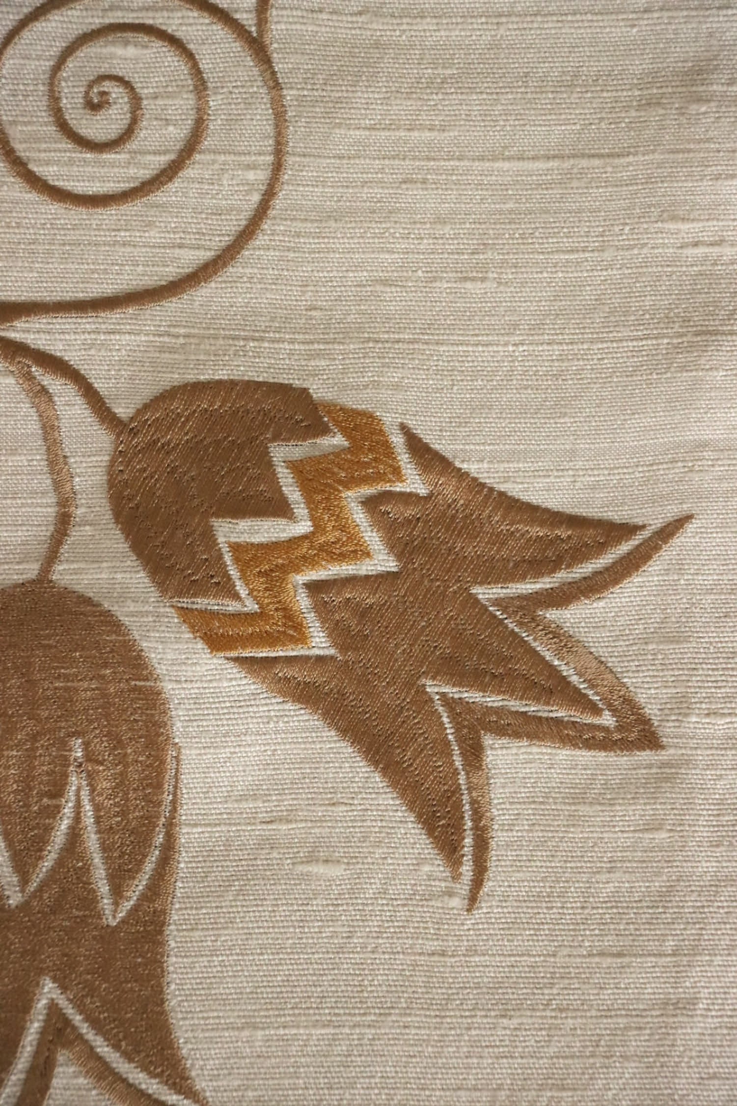 Close-up of MOREEN CAMEL silk fabric from Arte Fresca Outlet, revealing the intricate details of its fine embroidered floral motifs in brown, the soft camel base, and the tactile, raised quality of the exquisite silk and embroidery.