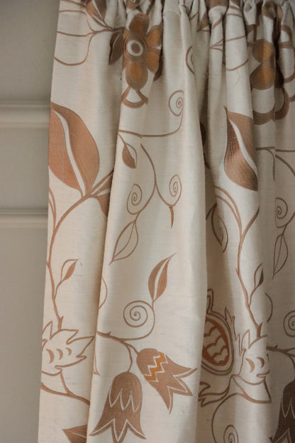 MOREEN CAMEL silk fabric from Arte Fresca Outlet, elegantly folded in soft drapes like a curtain, showcasing its fluid quality, the subtle embroidered floral pattern, and its suitability for creating serene, classic window treatments.