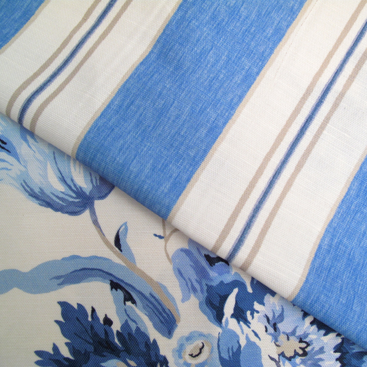 A close-up of patterned fabric with broad blue and off-white vertical stripes on the upper portion and a blue floral print on the lower portion.