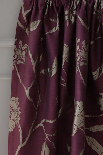 PENCARROW DARK RED silk fabric from Arte Fresca Outlet folded like a curtain, demonstrating its elegant drape, subtle sheen, and the beautiful flow of its dark red and gold-silver floral design, perfect for luxurious drapes.