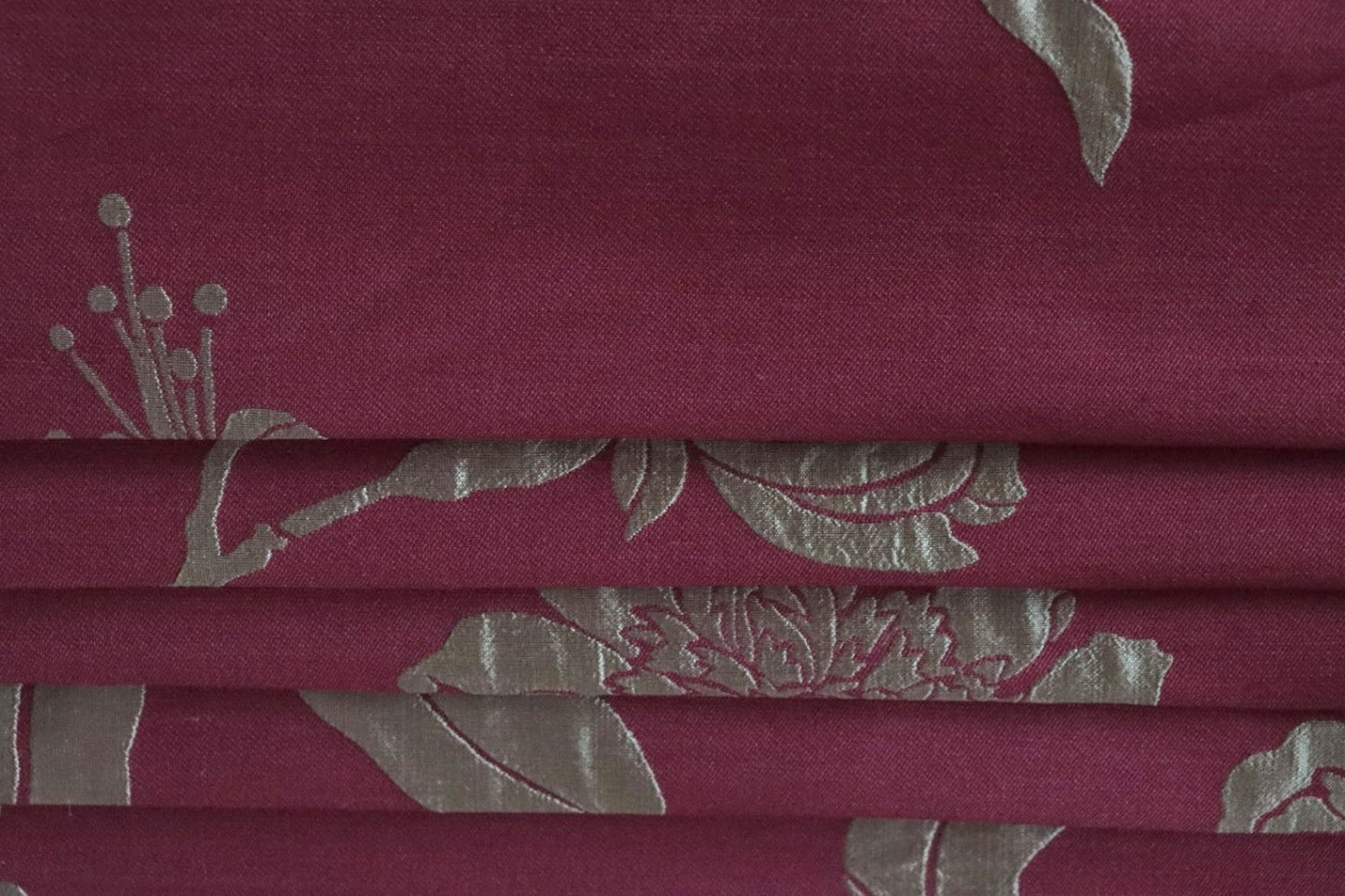 PENCARROW RASPBERRY GOLD silk fabric by Arte Fresca Outlet, folded precisely like a Roman blind, highlighting its structured yet soft nature, the clear definition of its gold floral pattern, and its ability to create sophisticated, richly textured window coverings.