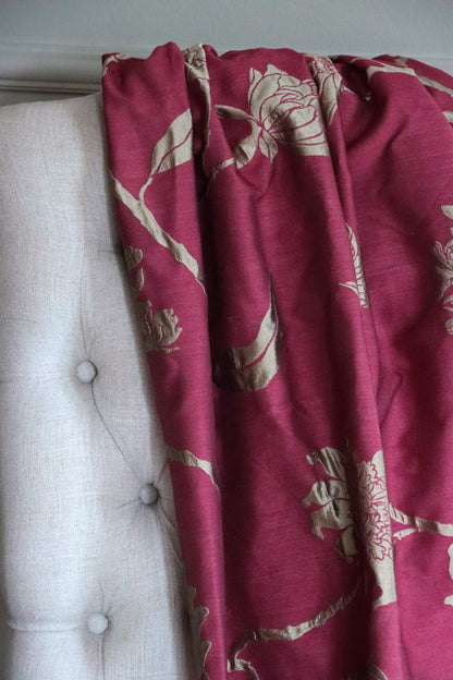 PENCARROW RASPBERRY GOLD silk fabric by Arte Fresca Outlet draped loosely over a light upholstered chair back, illustrating the grand scale of its gold floral pattern on raspberry red, ideal for assessing design repeat and elegant drape.