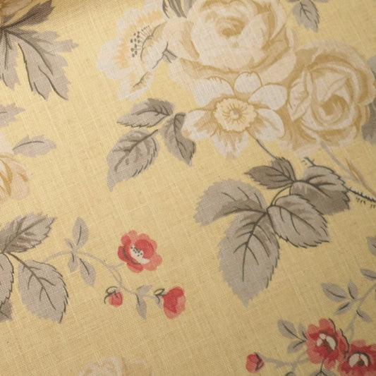  Close-up of PHILIPPA CAMOMILE fabric from Arte Fresca Outlet, revealing the detailed floral rose motifs in cream-white and red, subtle leaf vein drawing, and the distinct linen-like texture on its soft yellow ground, characteristic of this printed design.
