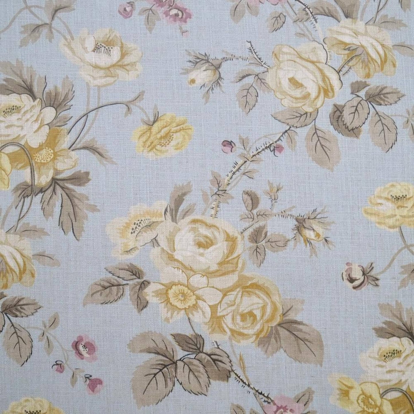 Close-up of PHILIPPA PALE BLUE fabric from Arte Fresca Outlet, revealing the detailed rose, blossom, and leaf motifs, soft cream, pink, and muted grey tones on a pale blue linen blend with subtle woven texture.

