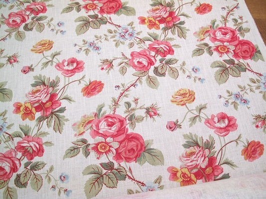 PHILIPPA PINK floral fabric by Arte Fresca Outlet, a full view displaying its romantic English country garden pattern with opulent roses in crimson and raspberry pink, delicate blue and golden yellow wildflowers, and green foliage on a woven off-white linen blend.