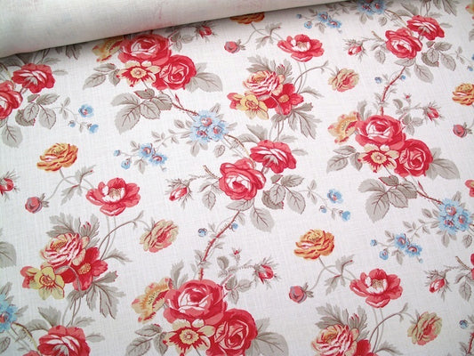 A close-up of a floral fabric with a vintage rose pattern on a cream background, featuring red, pink, yellow, and blue flowers with gray-green leaves.