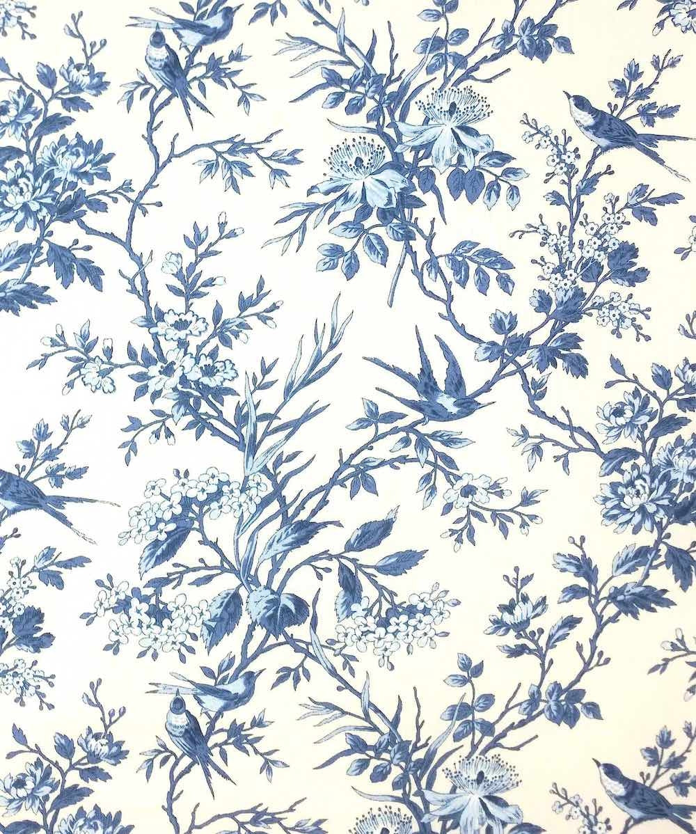 Blue and white floral toile pattern with birds and branches, shown as a close-up of fabric or wallpaper print.