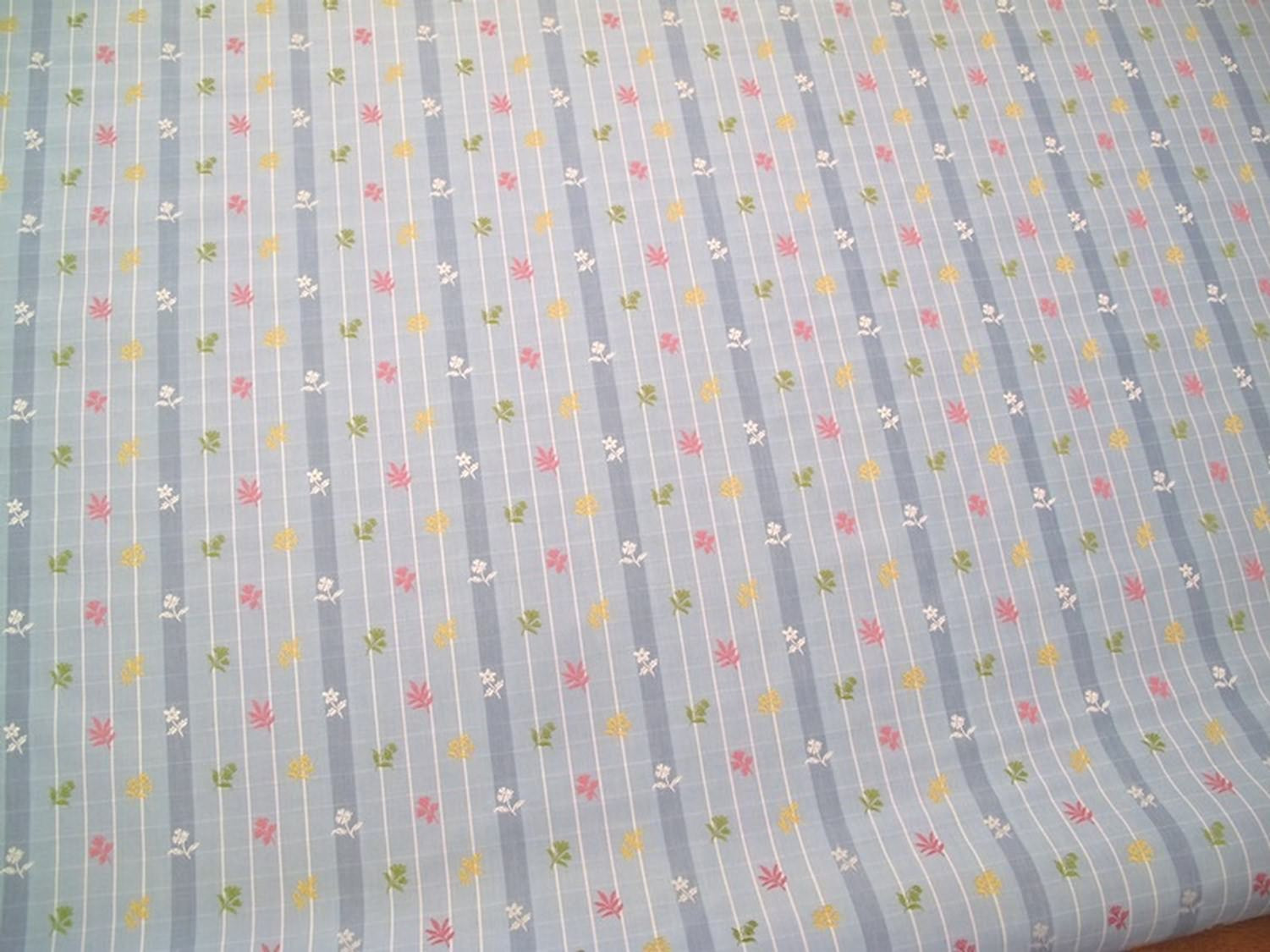 SHIRLEY BLUE fabric by Arte Fresca Outlet, a full view displaying its vertical blue stripes with white grid pattern and embroidered floral motifs in pink, yellow, and green, highlighting its charming English country style.