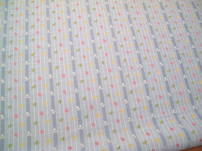 SHIRLEY BLUE fabric by Arte Fresca Outlet, a full view displaying its vertical blue stripes with white grid pattern and embroidered floral motifs in pink, yellow, and green, highlighting its charming English country style.