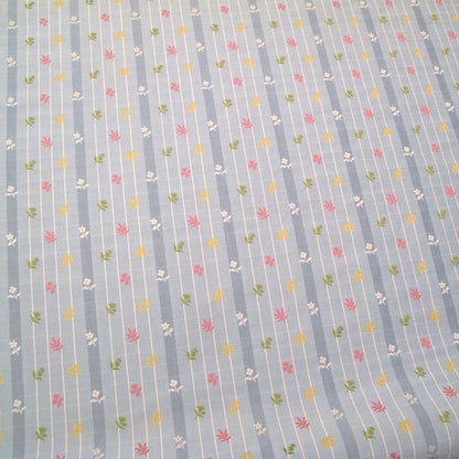 SHIRLEY BLUE fabric by Arte Fresca Outlet, a full view displaying its vertical blue stripes with white grid pattern and embroidered floral motifs in pink, yellow, and green, highlighting its charming English country style.