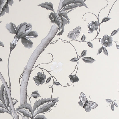 Close-up of SUMMER PALACE CHARCOAL wallpaper by Laura Ashley at Arte Fresca Outlet. The smooth paper surface reveals intricate plant tendrils, large blossoms, leaves, butterflies, and a delicate bird in varying shades of grey, anthracite, black, and white on a cream background, showcasing the pattern's drawing precision and depth.