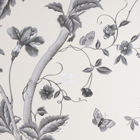 Close-up of SUMMER PALACE CHARCOAL wallpaper by Laura Ashley at Arte Fresca Outlet. The smooth paper surface reveals intricate plant tendrils, large blossoms, leaves, butterflies, and a delicate bird in varying shades of grey, anthracite, black, and white on a cream background, showcasing the pattern's drawing precision and depth.